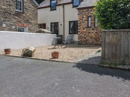 A stone building with a patio area, outdoor seating, and a wooden fence.