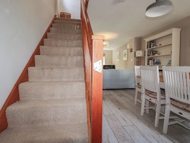 Una escalera que conduce a un dormitorio con una cama, una silla blanca y una estantería.