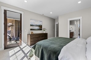 A bedroom with a bed, a dresser, a painting, and a view through an open door. - Brasada Ranchview Hot Tub | Fire Pit | Bunk Room (Powell Butte)