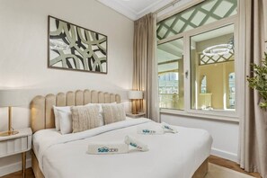 Ein Hotelzimmer mit Bett, Nachttischen, einer Lampe, einer Wanddekoration und einem Fenster mit Vorhängen.