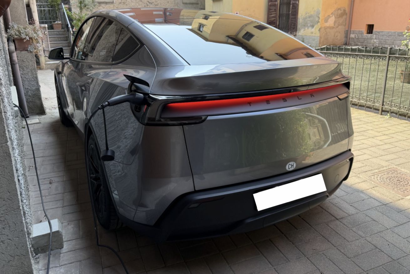 Ein geparktes Auto mit erkennbarem Kennzeichen und Blick auf ein Gebäude von hinten.