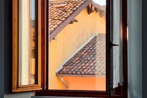 A window with a view of a building's roof and upper walls.