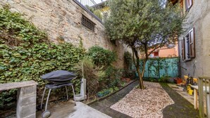 A stone wall, a tree, a grill, and a pathway in a courtyard. - A few minutes from Lake Como (Sun Tower) (Calolziocorte)