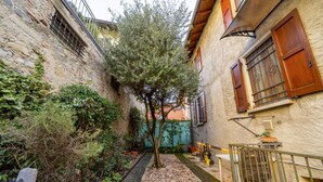 A narrow alleyway with a tree, stone walls, and a small garden area. - A few minutes from Lake Como (Sun Tower) (Calolziocorte)