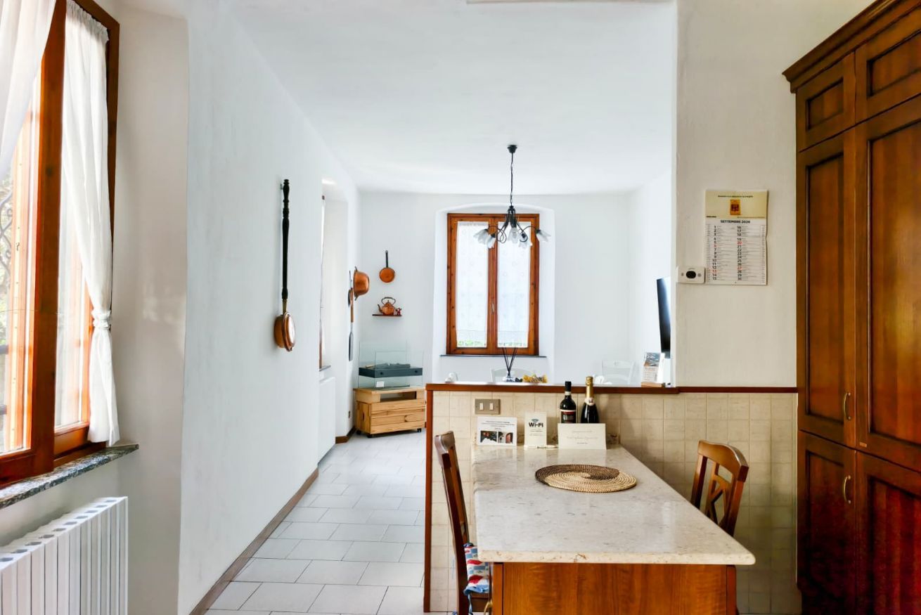 A kitchen with a central island, wooden cabinets, a window, and a hanging light fixture.
