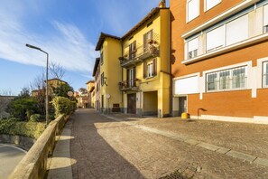 Una strada acciottolata fiancheggiata da edifici gialli e rossi, un cielo sereno e un lampione.