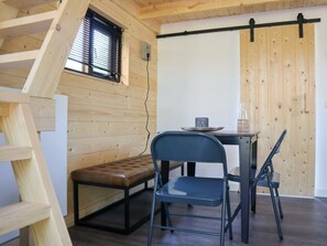 Ein Zimmer mit Schlafkoje, einer Bank, einem Tisch mit Stühlen und einer Schiebetür.