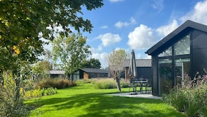 A modern building with large windows, a well-maintained lawn, and a patio area. - Holiday Home in Warmond With Terrace (Warmond)