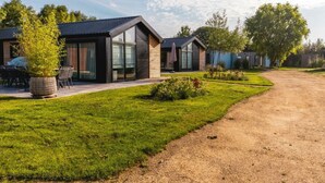 A modern residential area with houses featuring large windows, a well-maintained lawn, and a gravel driveway. - Holiday Home in Warmond With Terrace (Warmond)