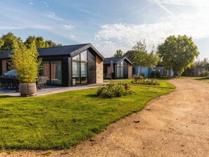 Ein modernes Wohngebiet mit Häusern, die große Fenster, einen gepflegten Rasen und einen Schotterweg zeigen.