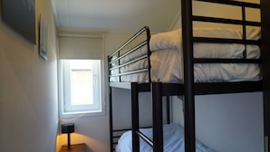 A bunk bed room with a window, a bedside table with a lamp, and a wall-mounted picture. - Holiday Home in Warmond With Terrace (Warmond)