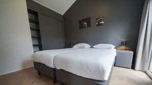 A modern bedroom with a bed, a nightstand, a lamp, and a window with curtains. - Holiday Home in Belfeld With Terrace (Belfeld)
