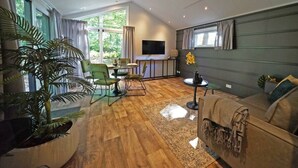 A modern living room with a wooden floor, a sofa, a TV, and a dining area with chairs and a table. - Holiday Home in Belfeld With Terrace (Belfeld)