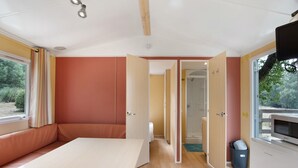 Una habitación con cama, televisión y ventana con cortinas.