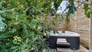 Un jacuzzi con cubierta de madera y un pérgola con hojas de roble.