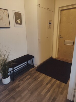Un couloir avec un banc, une porte et un interrupteur fixé au mur.