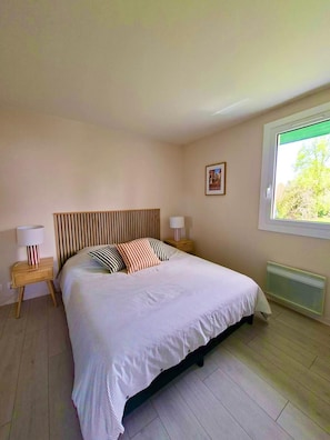 Ein Schlafzimmer mit einem Bett, zwei Nachttischen, einem Fenster und einer Heizung.