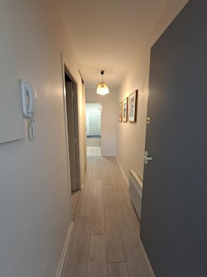 Ein Flur mit Telefon, einer Tür und gerahmten Bildern an der Wand.