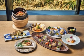 A variety of dishes on a wooden table with a view of a garden through a window.