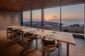 Área de refeições com vista para o oceano ao pôr do sol.
