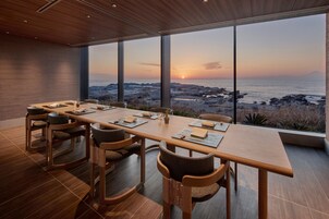 Un comedor con vista al océano al atardecer.