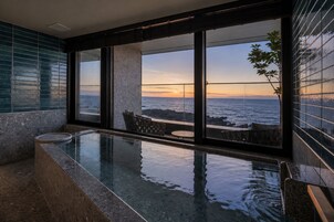 Una piscina infinita moderna con vista al océano al atardecer.