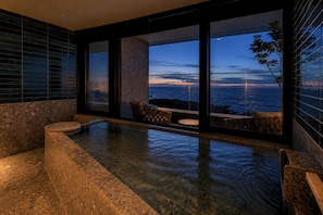 Um banheiro moderno com uma janela ampla, uma banheira e um espaço de estar com vista para o oceano.