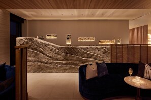 A modern interior with a seating area, a wall-mounted artwork, and a wooden ceiling.