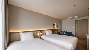 Habitación de hotel con dos camas, un escritorio, una silla y un armario.
