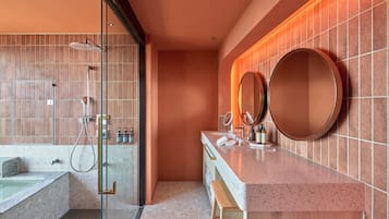 A modern bathroom with a glass-enclosed shower, a freestanding bathtub, and a vanity with a round mirror.