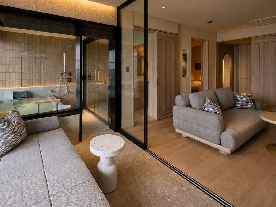 A modern living room with a glass partition, a sofa set, a coffee table, and a small round table.