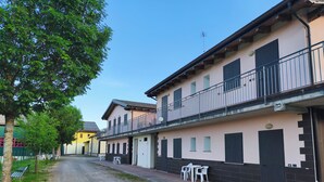 A street with buildings, a tree, and outdoor furniture. - Ostello di Montefiorino (Montefiorino)