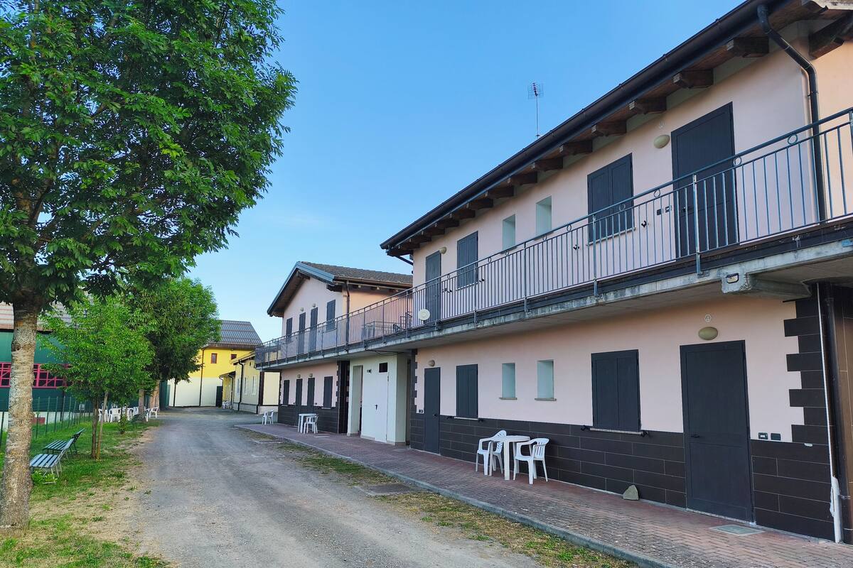 Rua com edifícios, uma árvore e mobiliário de exterior.