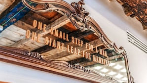 Un miroir orné de motifs métalliques complexes, portant l’inscription : « Un petit pas pour l’homme, un bond de géant pour l’humanité ! »