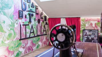 A room with a colorful floral wallpaper, a large sign with the name 'GREAT TAI,' a wooden floor, and a red curtain.