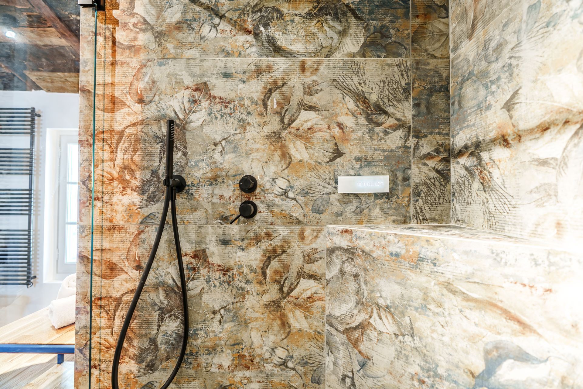 A shower with a glass enclosure and a marble-like wall.