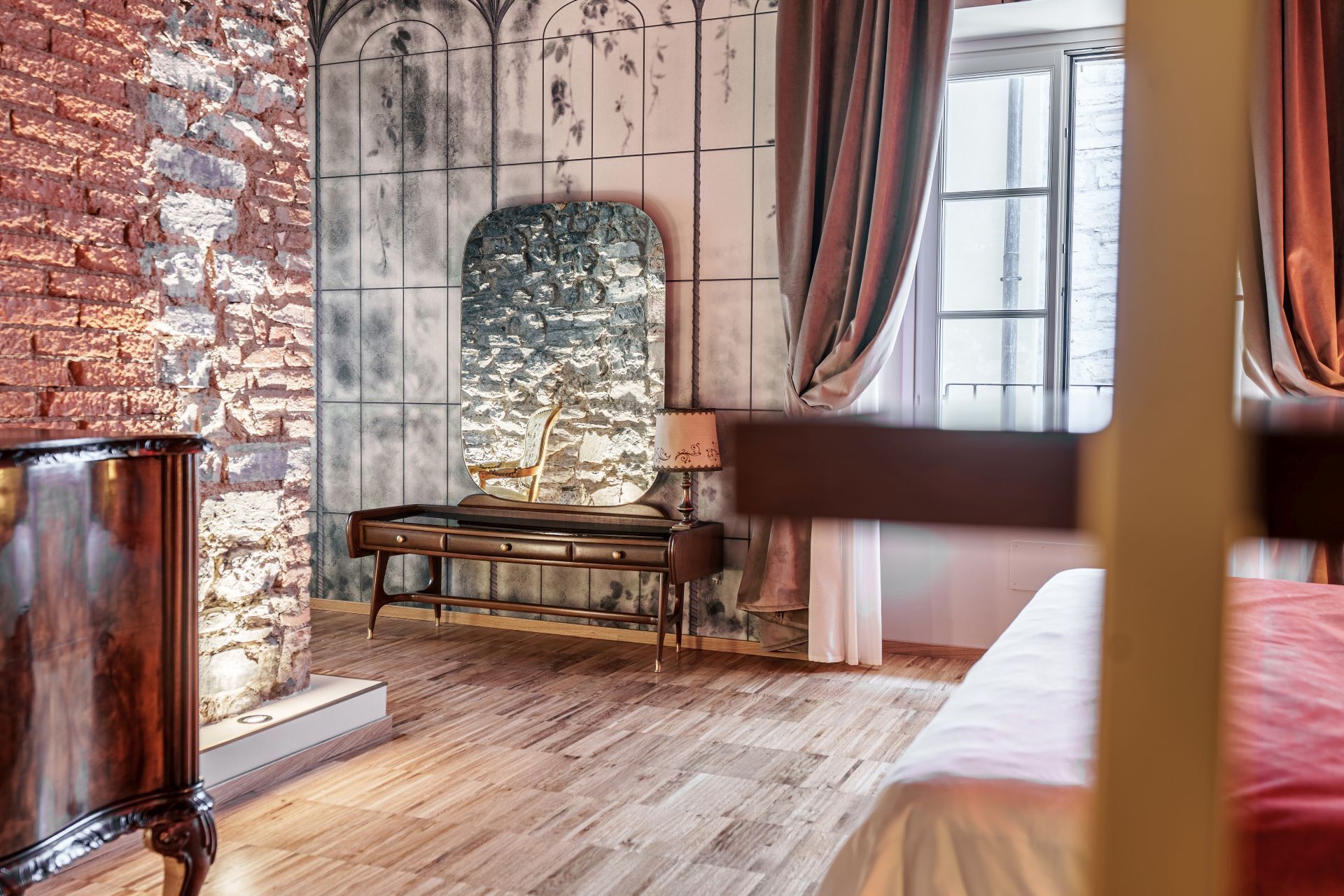 A room with a brick wall, a stone fireplace, a wooden bed, and a window with curtains.