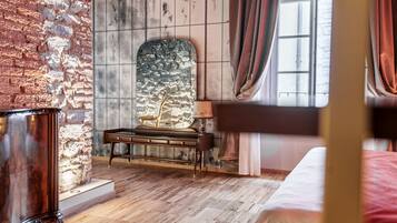Una habitación con pared de ladrillo, chimenea de piedra, cama de madera y ventana con cortinas.