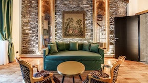 Une pièce avec un mur en pierre, un canapé vert, des fauteuils à motifs léopard et une table ronde.