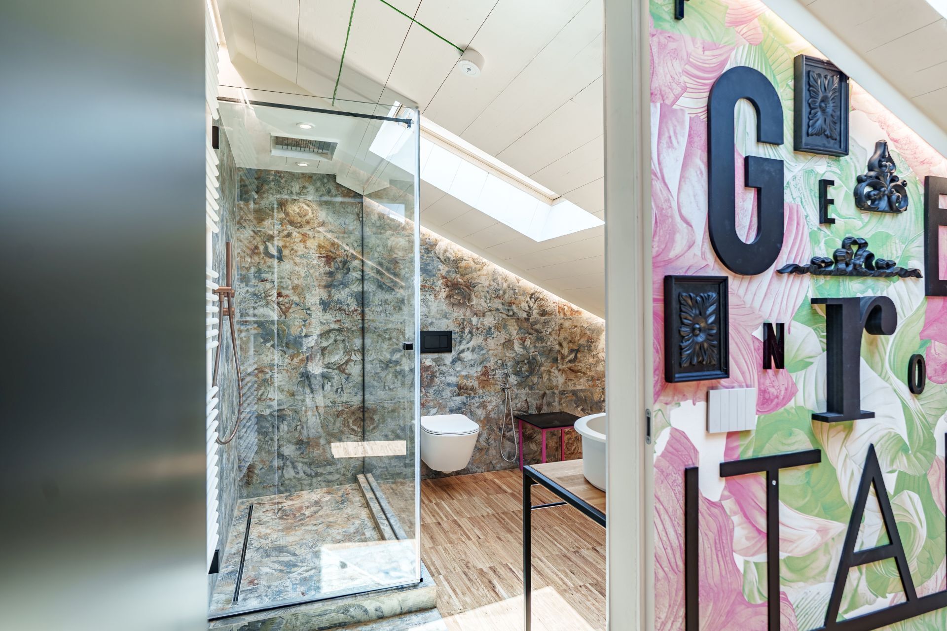 Ein modernes Badezimmer mit Glasabtrennung, Dusche und Waschbecken.