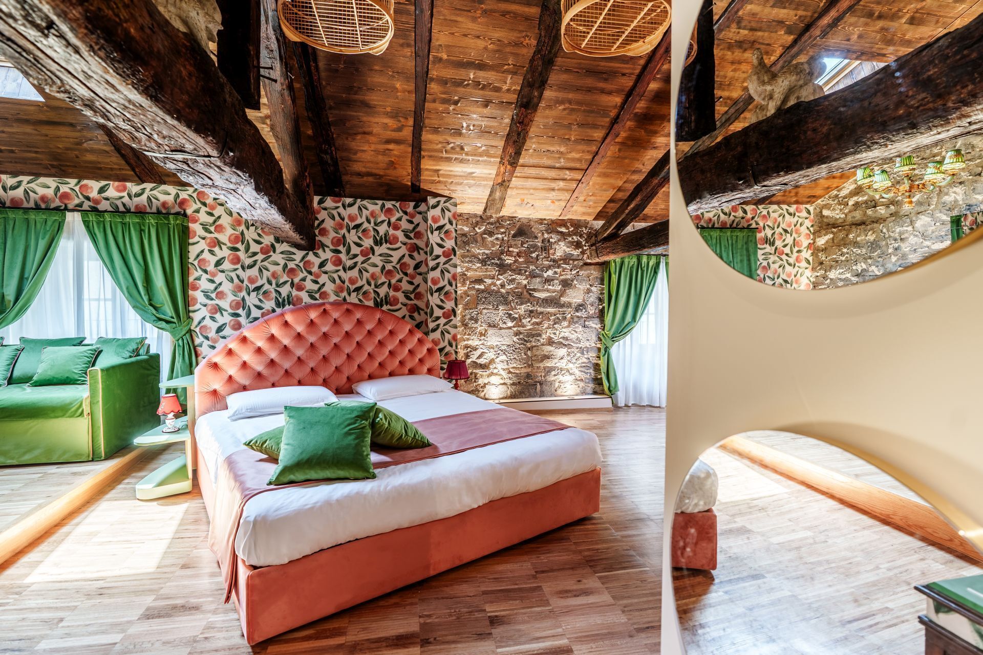 Une chambre avec un grand lit, des poutres en bois, un mur en pierre et un canapé vert.
