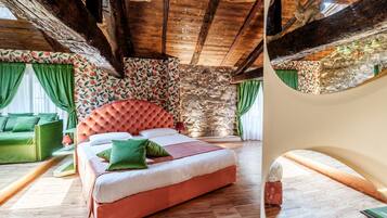Une chambre avec un grand lit, des poutres en bois, un mur en pierre et un canapé vert.