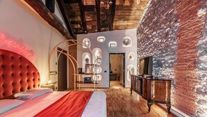 Une chambre d’hôtel avec un grand lit, un mur en briques et un plafond en bois.