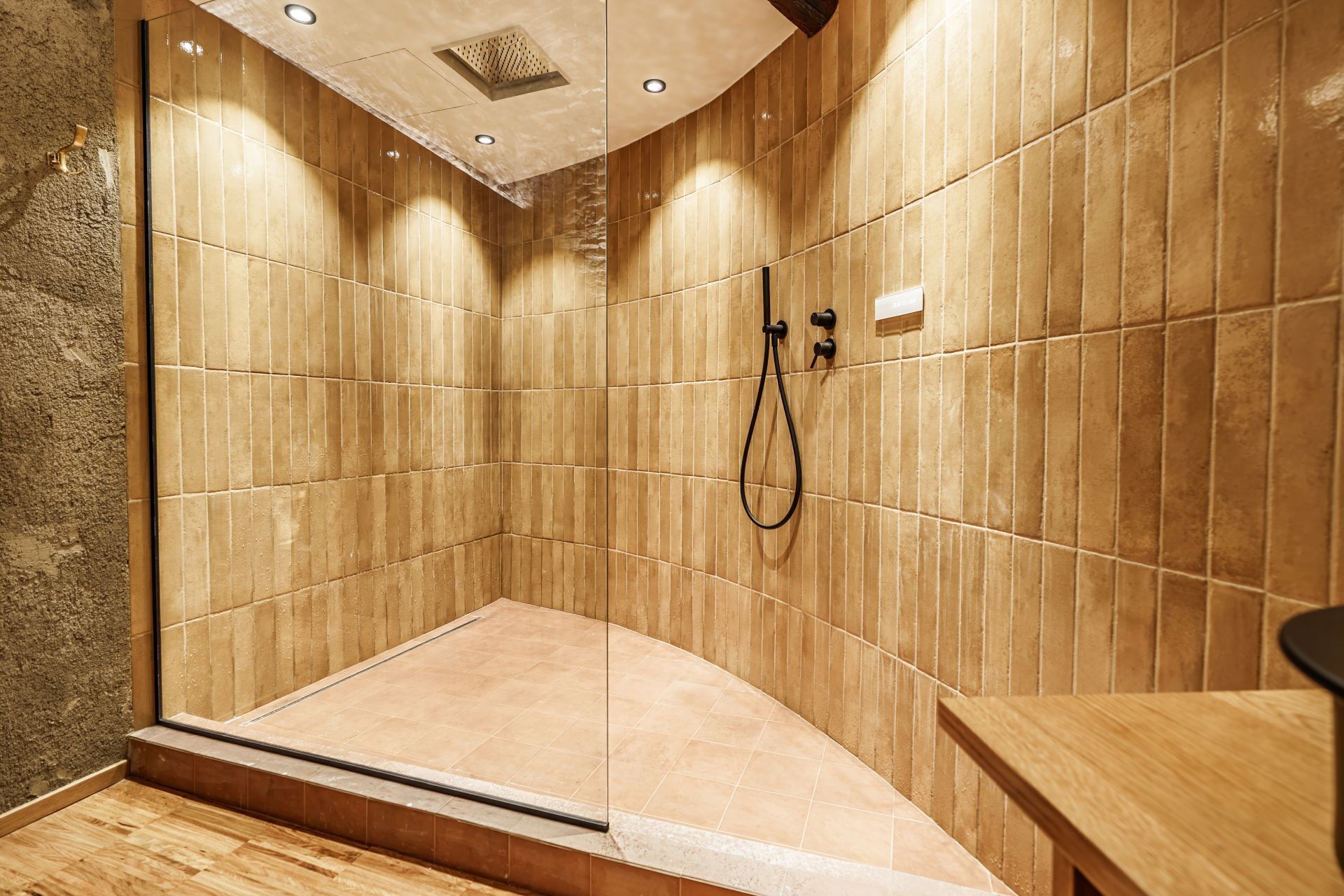 A shower area with tiled walls and a wooden floor.