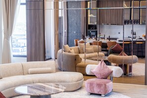 A modern living room with a sectional sofa, a round coffee table, and a pink ottoman.