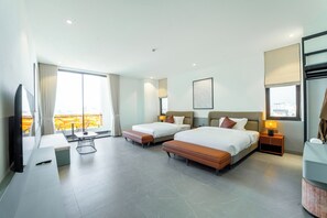 A hotel room with two beds, a TV, a desk, a chair, a window with curtains, and a balcony view.