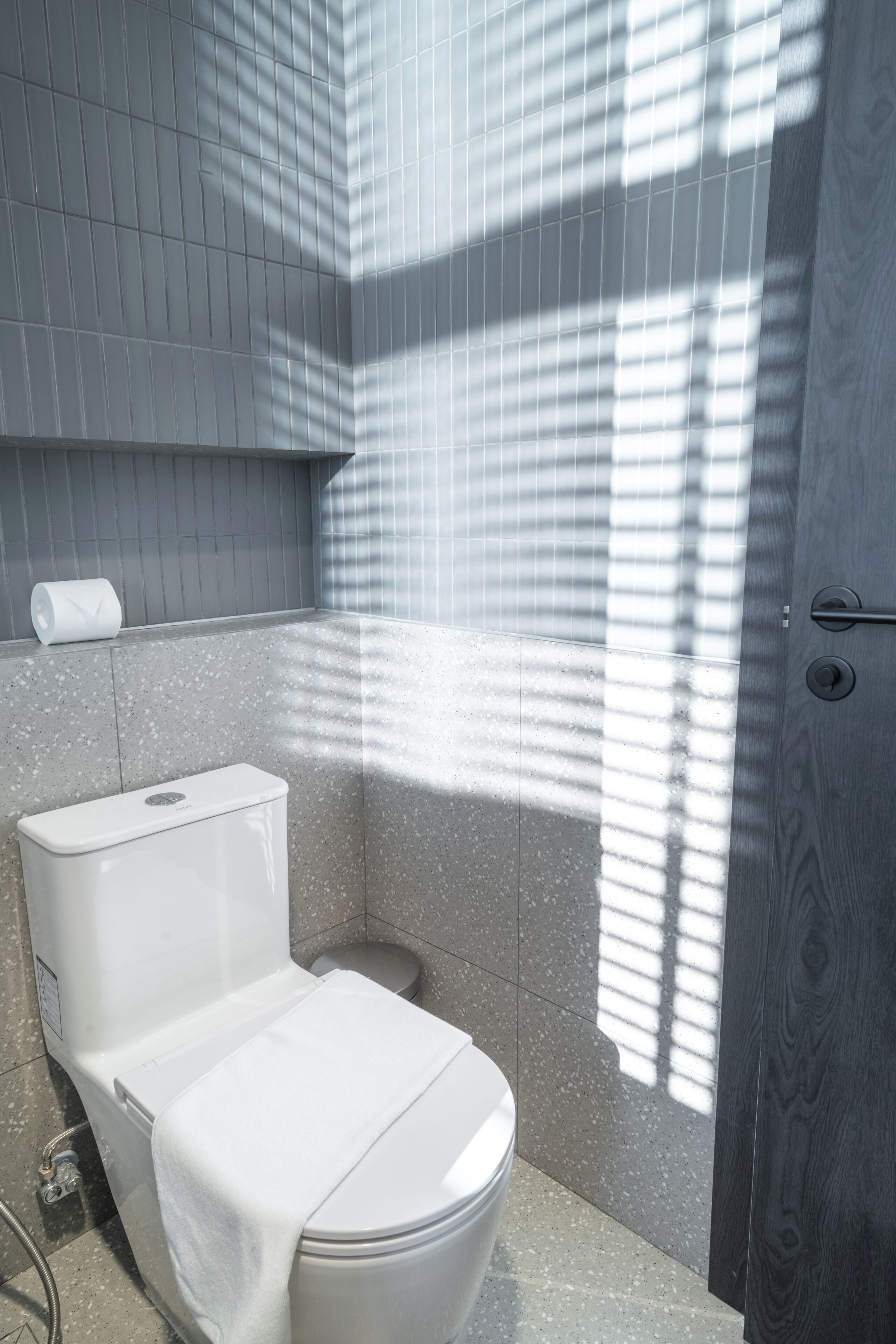 A bathroom with a toilet, a shower, and a towel rack.