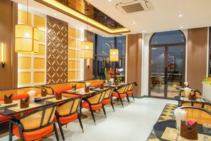 A restaurant with a long table, orange chairs, and decorative wall panels.