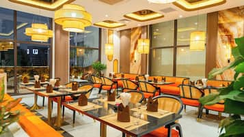A restaurant with multiple tables, chairs, and hanging lamps.