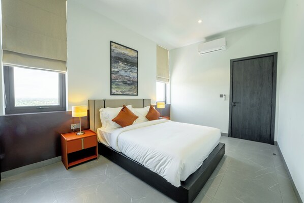 A modern bedroom with a bed, bedside tables, a painting, and a door.